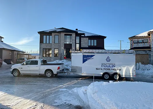 Camionnette et remorque Les Gouttières Poulin devant une résidence neuve